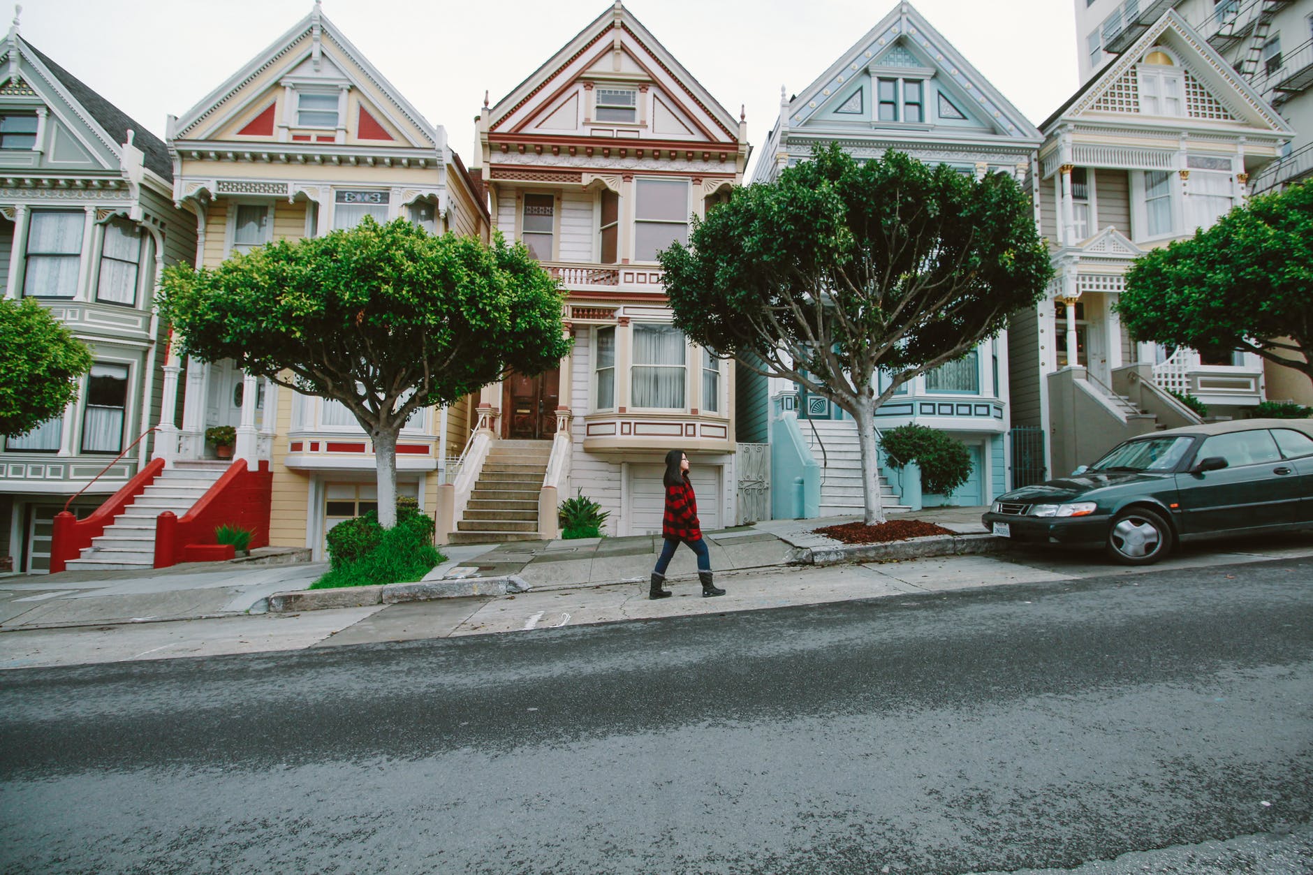 woman walking toward black sedan parked in front of colorful houses